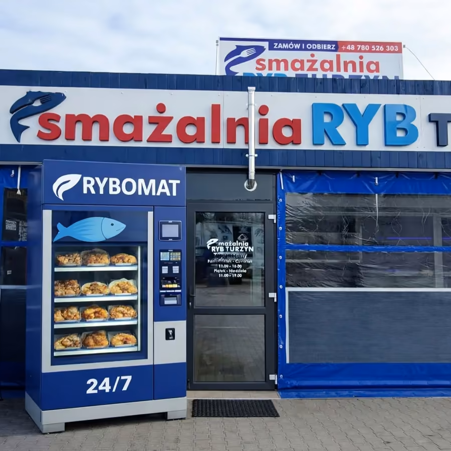 Wejście do smażalni: niebieski szyld i automat Rybomat 24/7